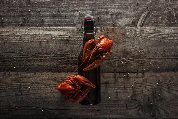 Top view of red lobsters and bottle with beer on wooden surface — Stock Photo