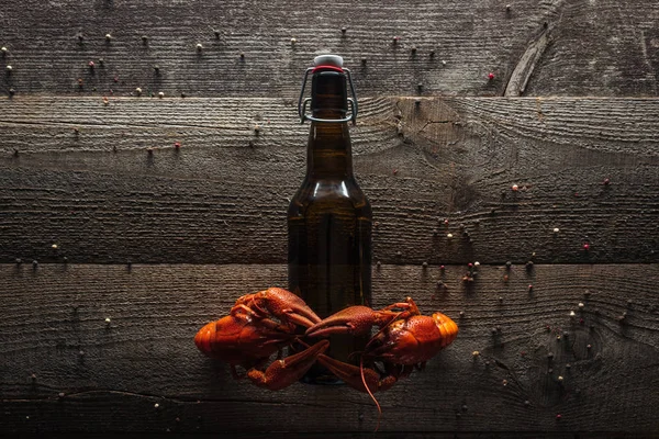Top view of red lobsters on bottle with beer at wooden surface — Stock Photo