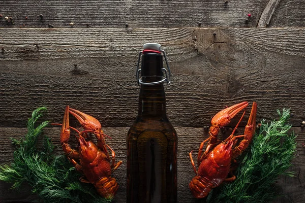 Top view of red lobsters, dill and bottle with beer on wooden surface — Stock Photo