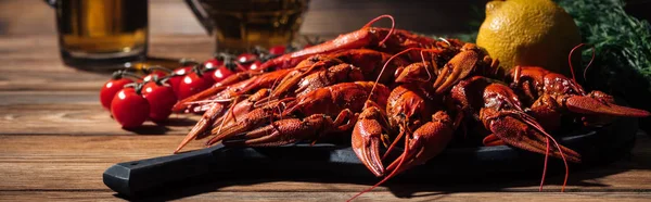 Colpo panoramico di aragoste rosse, pomodori, aneto, limone e bicchieri con birra sulla superficie di legno — Foto stock