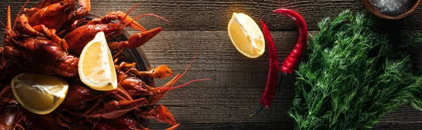 Tiro panorâmico de lagostas vermelhas, endro, pimenta e limão fatias na superfície de madeira — Stock Photo