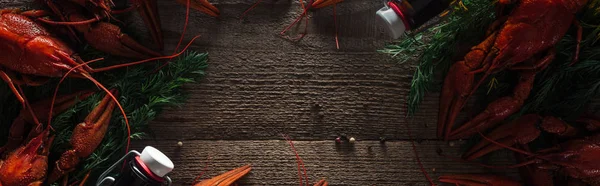 Tiro panorâmico de lagostas vermelhas, endro e garrafas de vidro na superfície de madeira — Fotografia de Stock