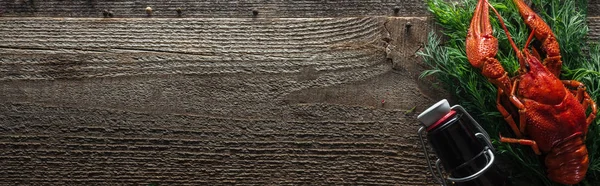 Foto panoramica di aragoste rosse, aneto e bottiglia di vetro su superficie in legno — Foto stock