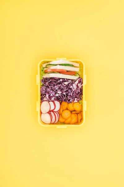 Vista superior da lancheira com sanduíches e legumes no fundo amarelo — Fotografia de Stock