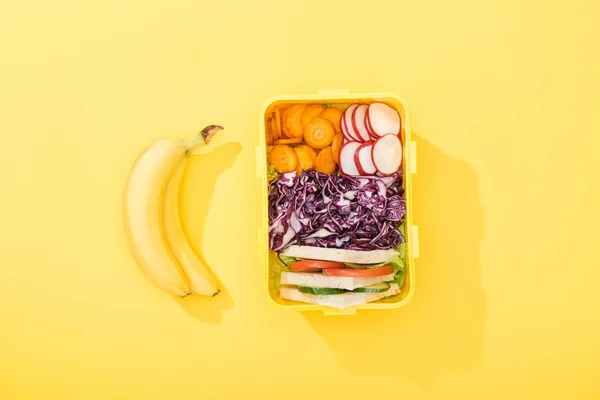 Vue du haut de la boîte à lunch avec sandwichs et légumes près des bananes — Photo de stock