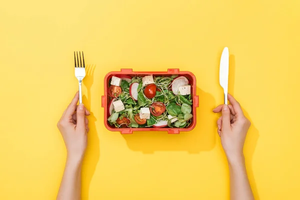 Vue recadrée de la femme tenant fourchette et couteau sur la boîte à lunch avec salade — Photo de stock