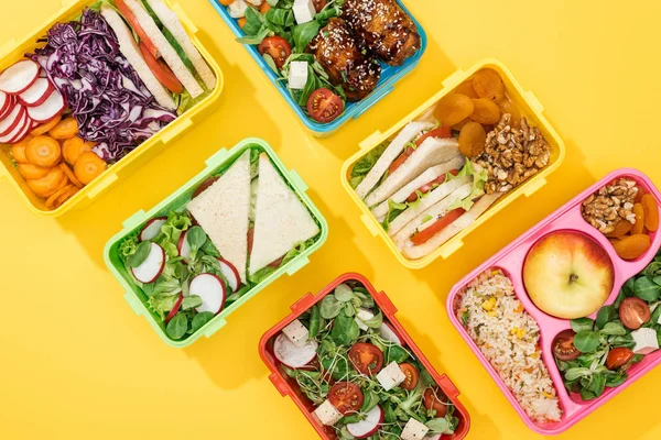 Top view of lunch boxes with food on yellow background — Stock Photo