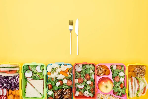 Vue du dessus de la fourchette et du couteau près des boîtes à lunch avec nourriture — Photo de stock