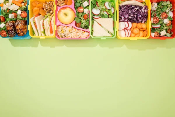 Vista superior de las loncheras con comida sobre fondo verde - foto de stock