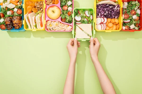Cropped view of woman choosing lunch boxes with food — Stock Photo