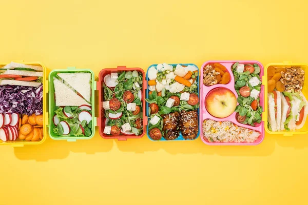 Top view of lunch boxes with delicious food on yellow background — Stock Photo
