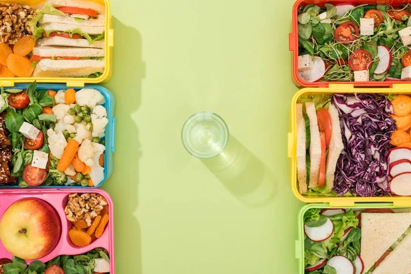 Вид на обеденные коробки с едой возле стакана воды — стоковое фото