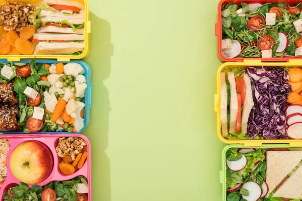 Draufsicht auf Lunchboxen mit Lebensmitteln auf grünem Hintergrund mit Kopierraum — Stockfoto