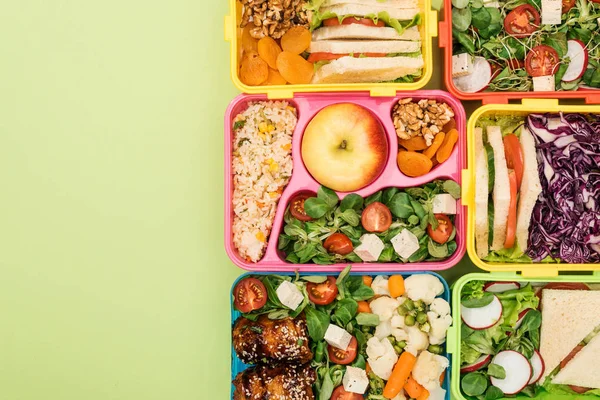 Draufsicht auf Lunchboxen mit Lebensmitteln auf grünem Hintergrund — Stockfoto