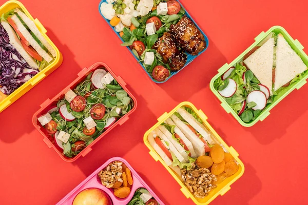 Draufsicht auf Lunchboxen mit Lebensmitteln auf knallrotem Hintergrund — Stockfoto