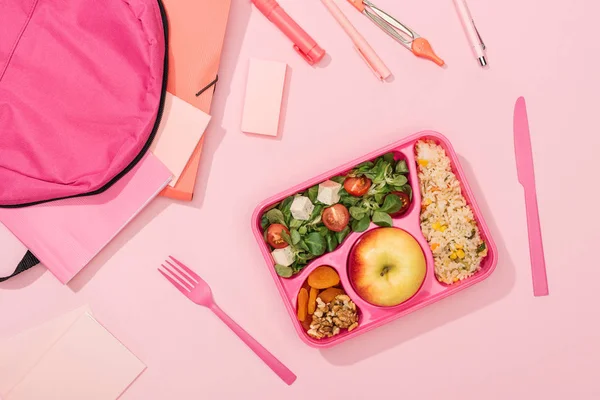 Vue du dessus de la boîte à lunch avec nourriture près du sac à dos et de la papeterie — Photo de stock