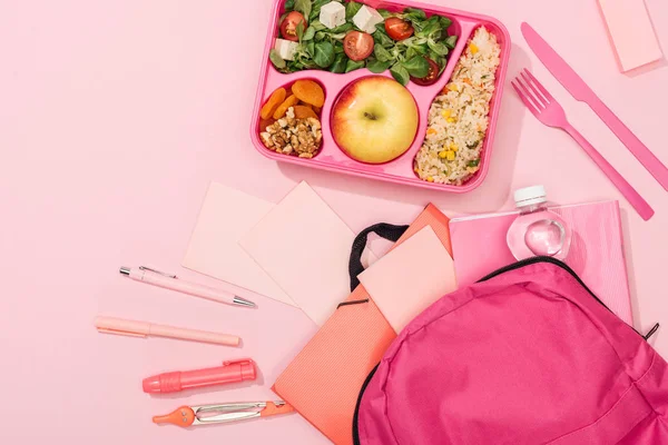 Top view of lunch box with food near backpack and stationery — Stock Photo