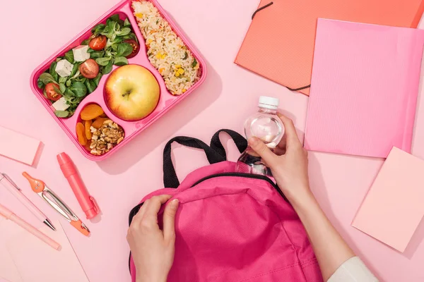 Cropped view of woman packing backpack near lunch box and stationery — Stock Photo