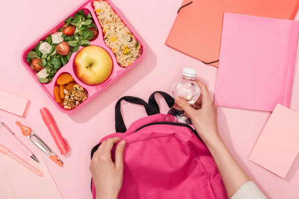 Ausgeschnittene Ansicht einer Frau, die in der Nähe von Lunchbox und Schreibwaren ihren Rucksack packt — Stockfoto