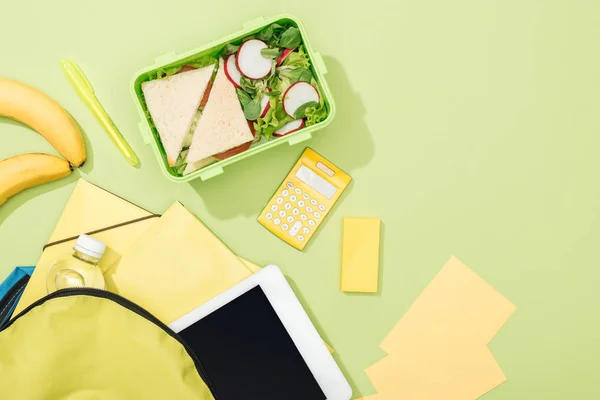 Vista superior da lancheira com sanduíches e salada perto da mochila com artigos de papelaria — Fotografia de Stock