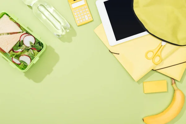 Vue du dessus du sac à dos avec tablette numérique près de la boîte à lunch, papeterie et bouteille d'eau — Photo de stock