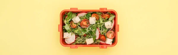 Panoramic shot of lunch box with salad on yellow background — Stock Photo