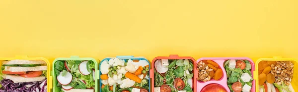 Panoramic shot of lunch boxes with tasty food on yellow background — Stock Photo