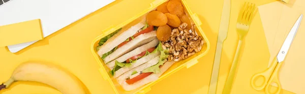 Tiro panorâmico de lancheira com comida perto de banana, faca e garfo — Fotografia de Stock