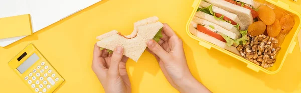 Cropped view of woman holding sandwich in hands near lunch box — Stock Photo