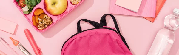 Panoramic shot of lunch box with food near backpack and stationery — Stock Photo