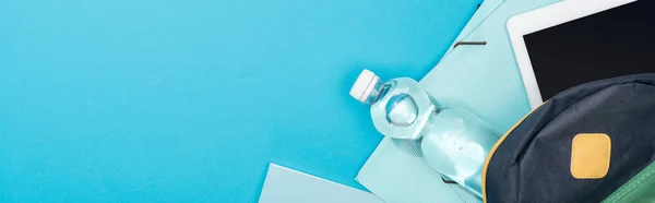 Panoramic shot of backpack with folders, stationery, bottle of water and digital tablet — Stock Photo