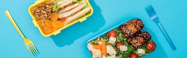 Panoramic shot of lunch box with food near plastic utensils — Stock Photo