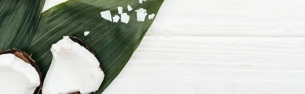 Vista superior de pedaços de coco em folhas de palma na superfície de madeira branca com espaço de cópia, tiro panorâmico — Fotografia de Stock