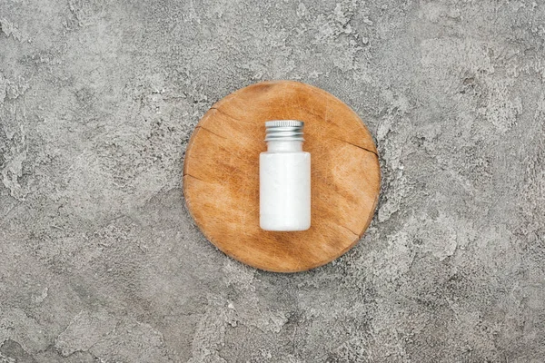 Vue du dessus du produit de beauté noix de coco en bouteille sur panneau en bois sur fond texturé gris — Photo de stock