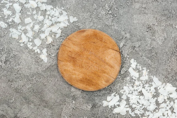 Vista superior de raspas de coco perto de tábua de madeira em fundo texturizado cinza — Fotografia de Stock