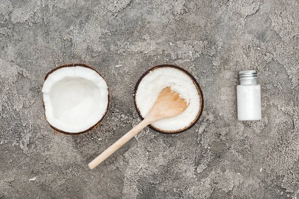 Plat avec noix de coco, cuillère en bois et crème de noix de coco sur fond texturé gris — Photo de stock