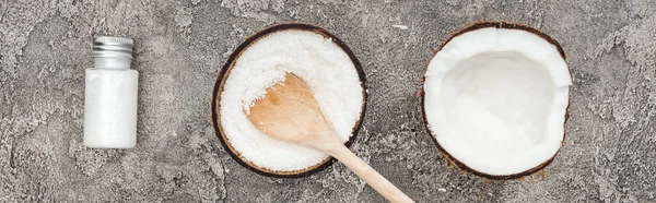Tendido plano con cocos, cuchara de madera y crema de coco sobre fondo de textura gris, plano panorámico - foto de stock