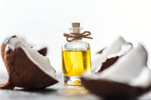 Selective focus of bottle with coconut oil near cracked coconuts isolated on white — Stock Photo