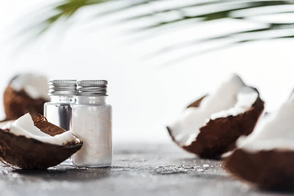 Selective focus of bottles with coconut cream and water near cracked coconuts — Stock Photo