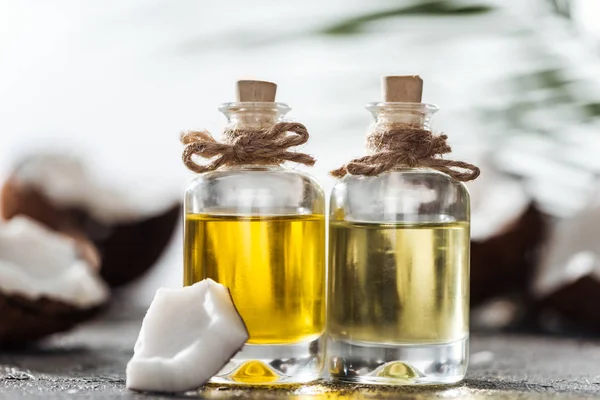 Selective focus of bottles with coconut oil near coconut piece — Stock Photo