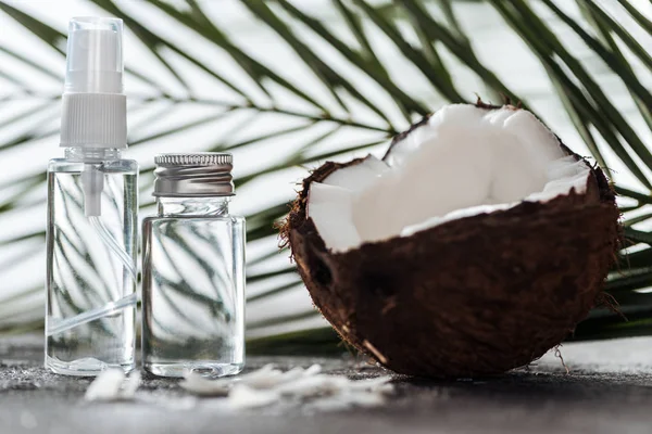 Selective focus of bottles with coconut water near palm leaf and cracked coconut — Stock Photo