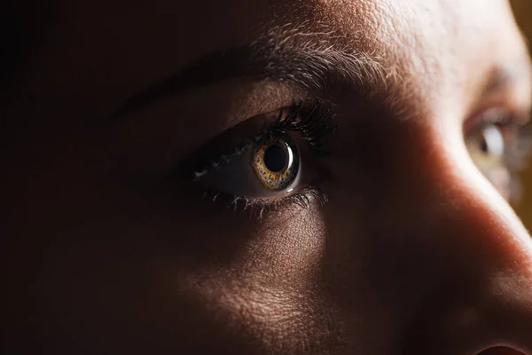 Vista da vicino della donna adulta occhio guardando lontano nel buio — Foto stock