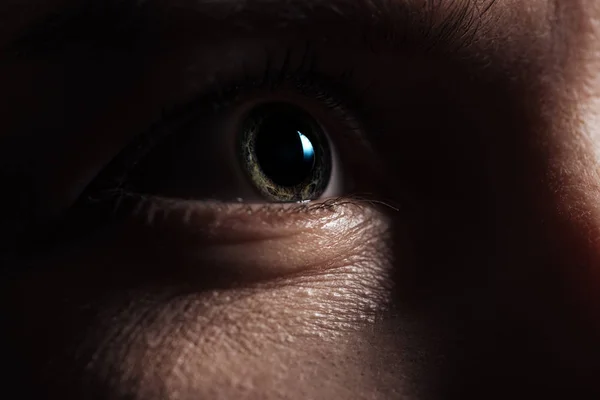 Крупный план глаза взрослого мужчины, глядящего вдаль в темноте — стоковое фото