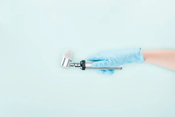 Vista recortada del médico en guante de látex que sostiene el dermatoscopio aislado en azul - foto de stock