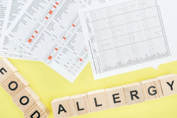 Top view of allergy test results near wooden blocks isolated on yellow — Stock Photo