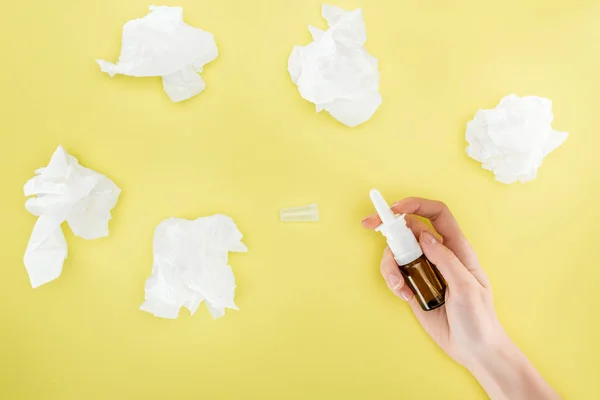 Cropped view of woman holding nasal spray near napkins isolated on yellow — Stock Photo