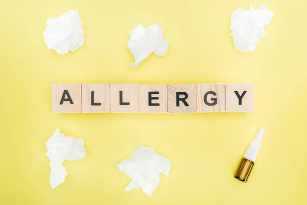 Top view of wooden blocks with word allergy near napkins and nasal spray isolated on yellow — Stock Photo