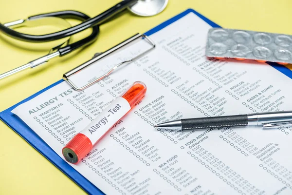 Tubo de ensaio e caneta em resultados de testes de alergia perto do estetoscópio no amarelo — Fotografia de Stock