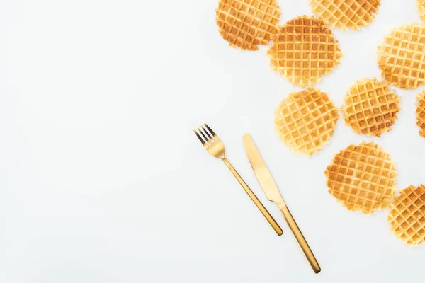 Vista superior de waffles espalhados e talheres dourados isolados em branco — Fotografia de Stock