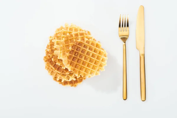 Vista superior de garfo dourado e faca perto de waffles em branco — Fotografia de Stock